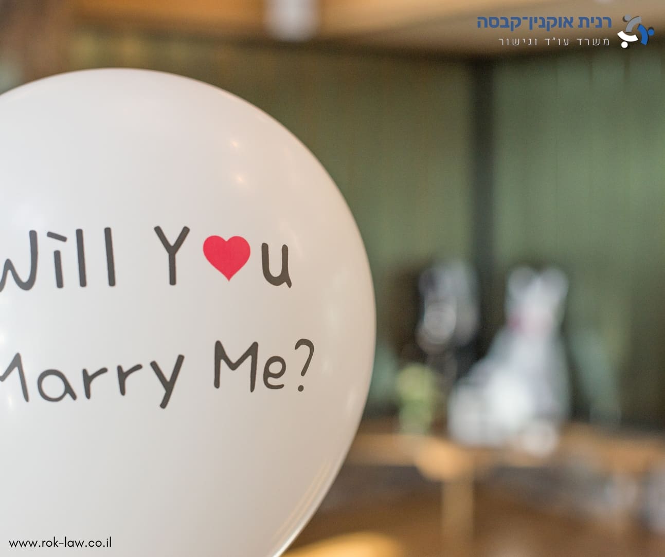 בלון לבן ועליו הכיתוב Will You Marry Me, חדר מטושטש ברקע