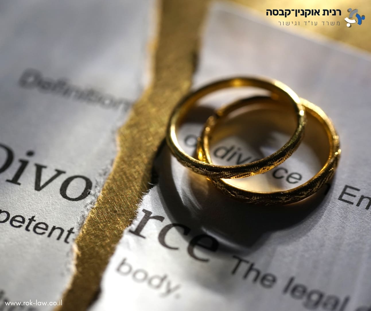 שתי טבעות נישואין מונחות על דף מילון שבו המילה Divorce, קרוע לשניים