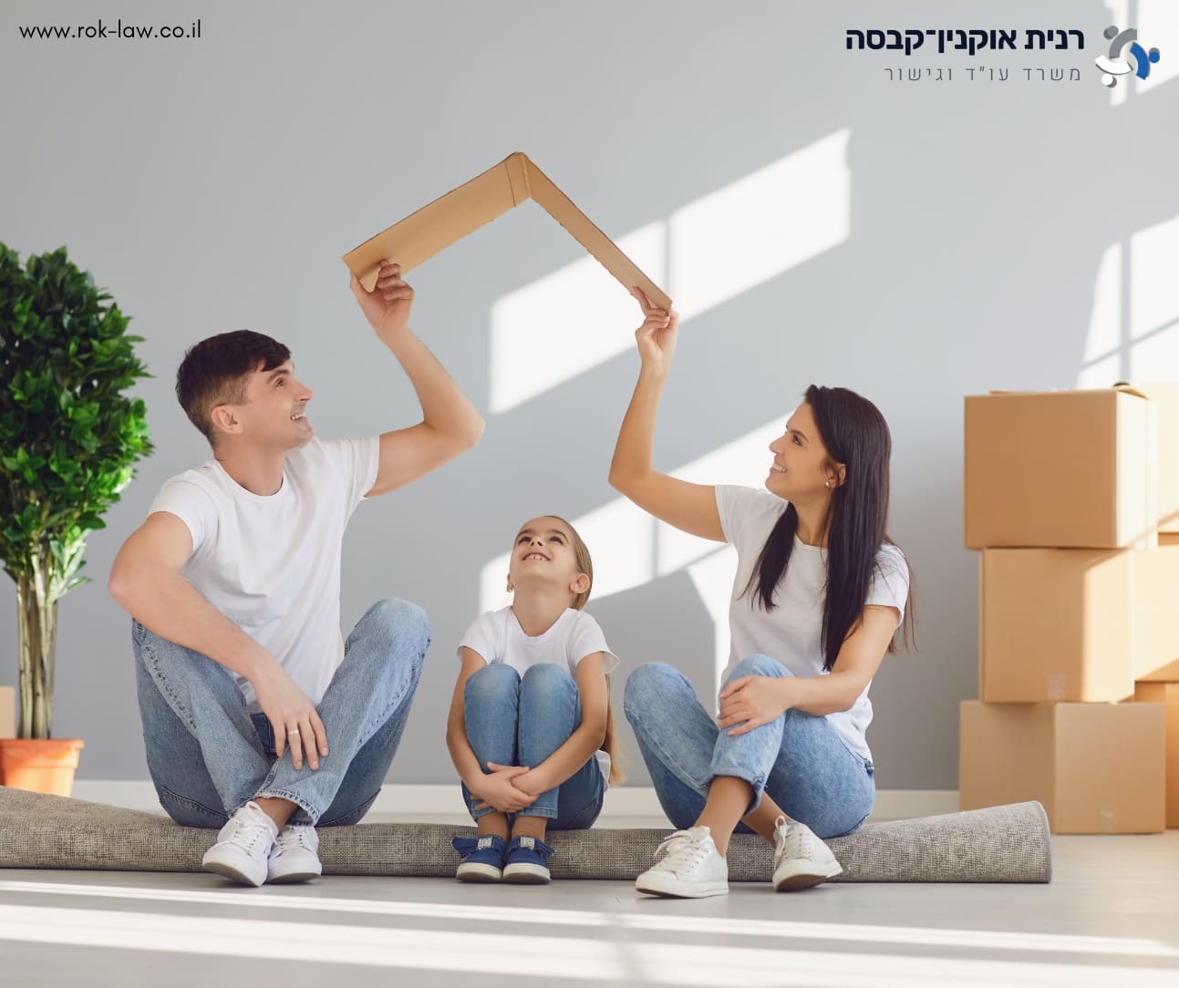 הורים וילדה יושבים על רצפת דירה, מחזיקים גג מקרטון מעל ראשה, ולצידם קרטוני מעבר דירה