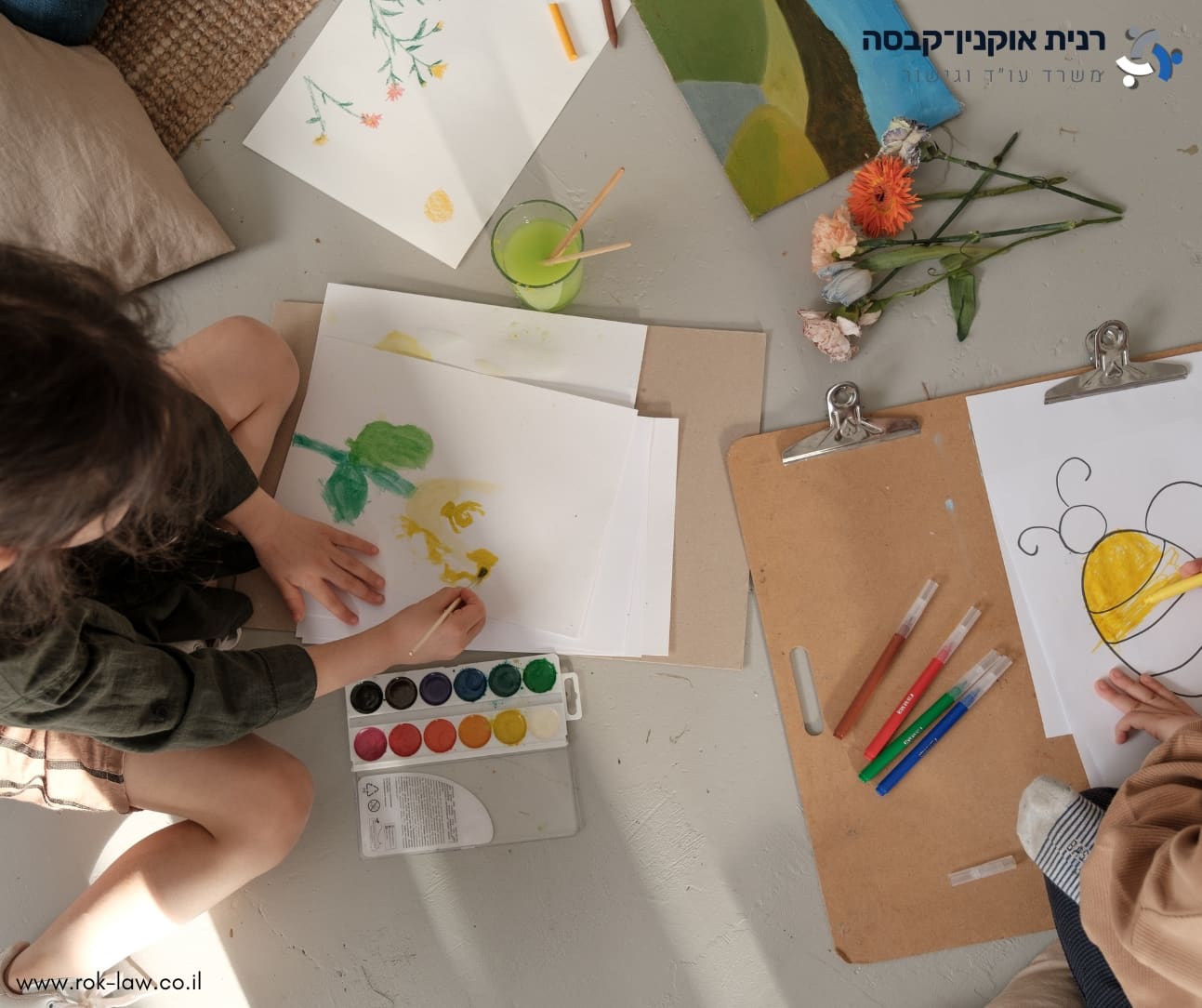 מבט מלמעלה על ילדים מציירים בצבעי מים על רצפה בהירה